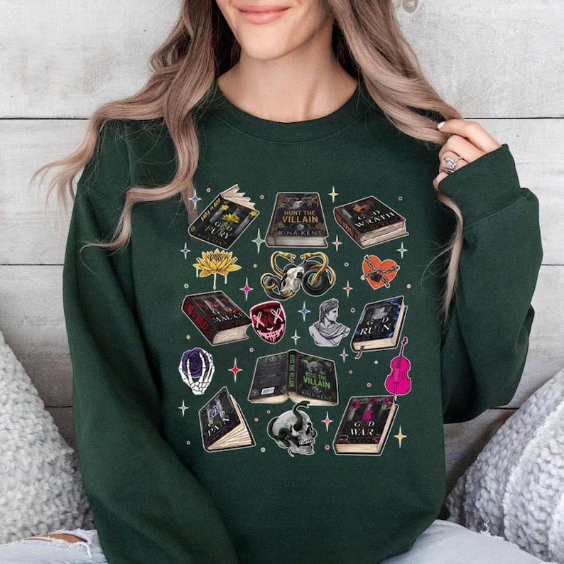May include: Dark green sweatshirt featuring a collection of illustrated books, skulls, and other fantasy-themed graphics. The design includes titles like "God Fury" and "Hunt the Villain". A unique and stylish apparel item.