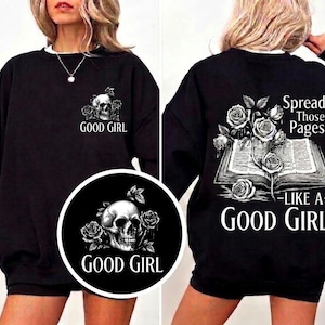 May include: Black sweatshirt with a white collar and the text "GOOD GIRL" with a skull and rose graphic on the front. The back features an open book with roses and the text "Spread Those Pages Like A Good Girl."