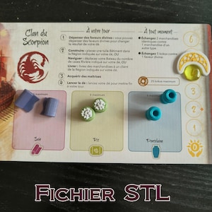 May include: A board game component set featuring various game pieces. Includes blue, green, and white tokens, along with a game board with French text. The game board has a scorpion emblem and the text "FICHIER STL".