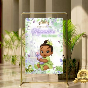 K&ouml;nnte beinhalten: Ein Babyparty-Schild mit einer Cartoon-Illustration eines kleinen M&auml;dchens in einem gr&uuml;nen Kleid, das eine Flasche h&auml;lt. Auf dem Schild steht "Willkommen zu Hannahs Babyparty" mit floralen und Schlossakzenten. Das Schild wird in einem goldenen Metallrahmen angezeigt.