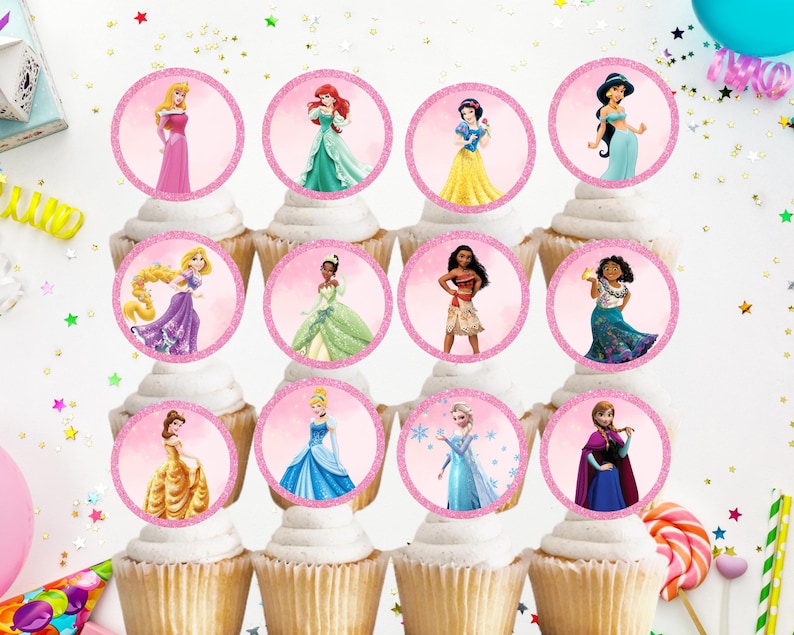 May include: Twelve pink cupcake wrappers with round edible images of Disney princesses. The princesses include Ariel, Belle, Cinderella, Elsa, Jasmine, Mulan, Pocahontas, Rapunzel, Snow White, Tiana, and  Moana.