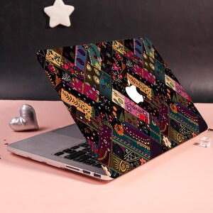 Może przedstawiać: Laptop z naklejką ochronną o ciemnym, wielokolorowym wzorze patchworkowym. Projekt składa się z r&oacute;żnych prostokątnych segment&oacute;w wypełnionych misternymi motywami kwiatowymi, geometrycznymi i botanicznymi w odcieniach złota, r&oacute;żu, turkusu i czerni.