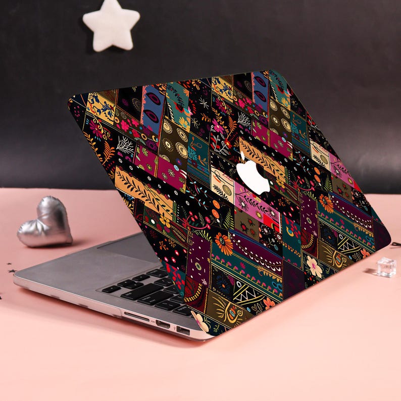 Może przedstawiać: Laptop z naklejką ochronną o ciemnym, wielokolorowym wzorze patchworkowym. Projekt składa się z r&oacute;żnych prostokątnych segment&oacute;w wypełnionych misternymi motywami kwiatowymi, geometrycznymi i botanicznymi w odcieniach złota, r&oacute;żu, turkusu i czerni.