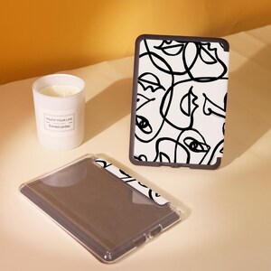 May include: A black and white abstract design printed on a clear plastic case for an e-reader. The case has a black border and is designed to protect the e-reader.