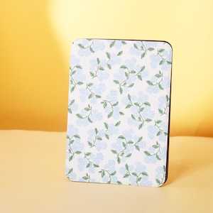 May include: A white coaster with a blue floral pattern. The coaster has a black border.