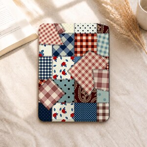 Könnte beinhalten: Eine rechteckige E-Reader-Hülle mit einem Patchwork-Design aus verschiedenen Stoffmustern, darunter rot-weißes Vichy-Karo, blau-weißes Schottenkaro, cremefarbene Stoffe mit roten Blumenmustern, dunkelblaue Stoffe mit weißen Punkten und dunkelrote Paisley-Motive.