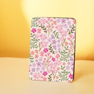 Puede incluir: Un posavasos blanco con un patrón floral con flores rosas, moradas y verdes. El posavasos está hecho de un material duradero y es perfecto para proteger las superficies del calor y los derrames.