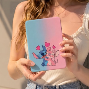 May include: A rectangular e-reader case featuring a blue and pink gradient background. The front displays a graphic of the blue character Stitch hugging the pink character Angel, surrounded by four small pink hearts floating above their heads.