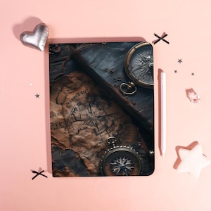 Może przedstawiać: Notatnik w stylu vintage z motywem mapy i dwoma zabytkowymi kompasami. Notatnik jest otwarty, ukazując szczegółową mapę. Kompasy są w odcieniach złota z misternymi detalami. Tło jest w kolorze jasnoróżowym.