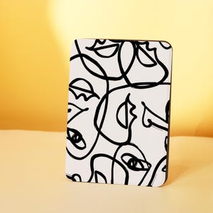 May include: Black and white abstract line art print featuring multiple stylized faces. The print is on a white background and has a modern minimalist aesthetic.