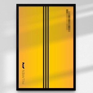 May include: A framed poster with a yellow gradient background and two vertical black stripes. The text "McLaren Pi" is printed in black at the bottom left. A blurred rectangular shape is in the top right corner.