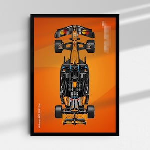 May include: A framed print featuring a top-down view of a McLaren MCL39 F1 car. The car is predominantly black and orange, with black wheels and intricate detailing. The background is a gradient of orange shades. The text "McLaren MCL39 F1 Car" is printed on the left side.