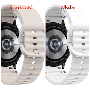 May include: Two smartwatches are shown, one with an off-white strap labelled "Starlight" and the other with a white strap labelled "White". Both watches have a black circular face with text that reads "Sapphire Crystal GPS - 5 ATM".