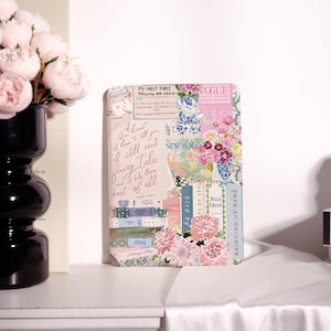 Könnte beinhalten: Ein dekoratives rechteckiges Kunstwerk mit einer Collage aus floralen und textlichen Elementen. Das Kunstwerk zeigt rosa und lila Blumen, Text aus der Zeitschrift Vogue und das Zitat "I still read fairy tales and I like them best of all."