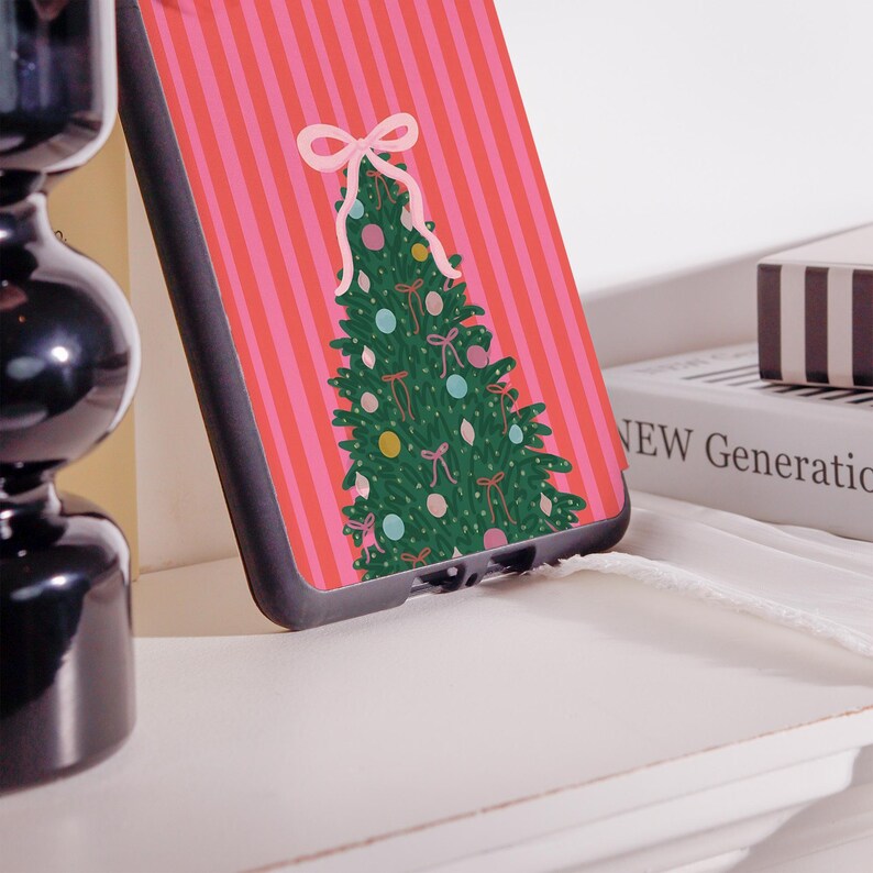 May include: A phone case featuring a Christmas tree design. The case has a pink and red striped background with a green Christmas tree decorated with bows and ornaments. The case is black.