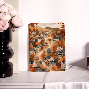 May include: A rectangular decorative tray featuring a detailed illustration of a village nestled in a valley during autumn. The artwork showcases white houses with dark roofs, surrounded by trees in shades of orange, red, and brown. A winding road leads through the village.