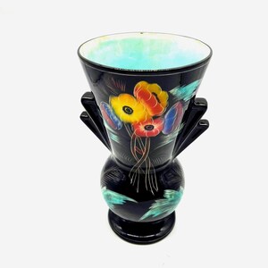 May include: Black ceramic vase with a floral design. The vase has two handles and a wide mouth. The flowers are painted in shades of red, yellow, blue, and green.
