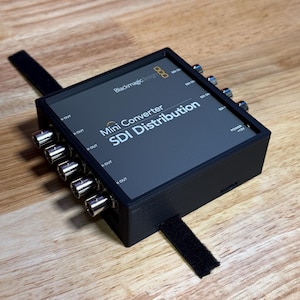 May include: Blackmagic Design Mini Converter SDI Distribution, a black box with multiple SDI outputs and a power input labeled "Power +12V".