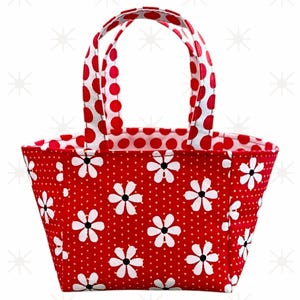 May include: A small red and white tote bag with a polka dot pattern and white daisy print. The bag has two handles.