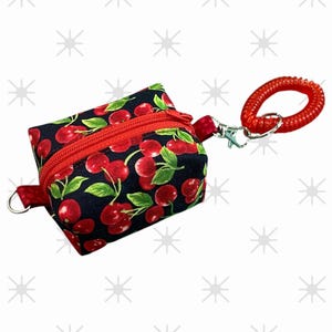 May include: A small black zippered pouch with a red cherry print and a red retractable keychain.