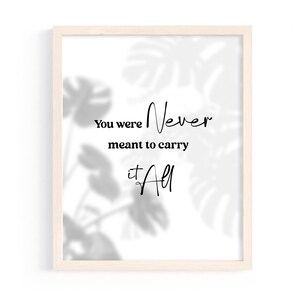 Puede incluir: Impresión enmarcada con las palabras "You were Never meant to carry it All" en escritura negra. El marco es de madera clara y el fondo tiene un patrón de hojas suave y borroso.