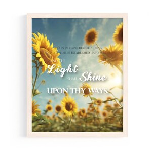 May include: A framed print featuring a field of sunflowers under a blue sky. The image includes the text "Light Shine Upon Thy Ways" and a Bible verse reference. The sunflowers are yellow and the frame is a light beige color.