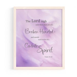 May include: A framed print with a light purple watercolor background. The text reads "The Lord nigh unto them that are of a Broken Hearted; and saveth such as be of a Contrite Spirit Psalm 34:18" in elegant script.