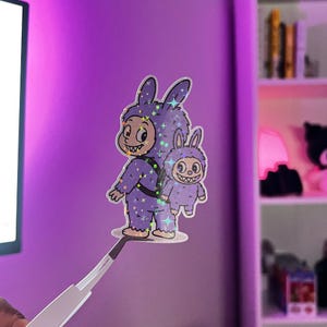 Pegatina de Labubu para mochila con conejito morado: vinilo con un adorable personaje de monstruo para diarios, portátiles y botellas de agua (holográfica)