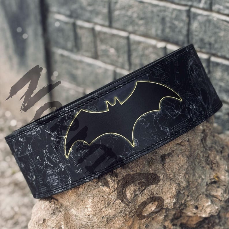 Peut inclure: Ceinture d'halt&eacute;rophilie noire avec le logo Batman brillant et un contour jaune. Le fond noir est orn&eacute; d'illustrations de style bande dessin&eacute;e. Con&ccedil;ue pour l'halt&eacute;rophilie et l'entra&icirc;nement en force, elle mesure environ 10 cm de large.