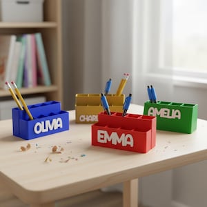 Puede incluir: Cuatro organizadores de escritorio coloridos, cada uno con un nombre diferente: OLIVA, EMMA, CHARI y AMELIA. Los organizadores son azules, rojos, dorados y verdes, y contienen bolígrafos y lápices. Están sobre una mesa de madera clara.