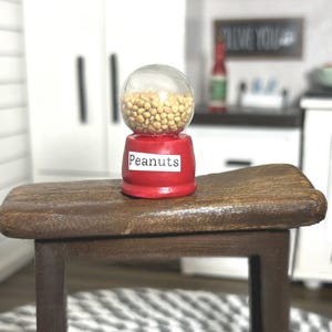 May include: A white ceramic mug with a black handle and the text "But First, Coffee" in a handwritten style. The mug is on a white surface. The mug is approximately 4 inches tall.