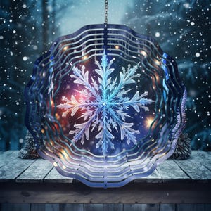 May include: A decorative, hanging snowflake ornament. The ornament features a detailed, multi-layered design with a central snowflake motif. The color palette includes shades of blue, white, and hints of orange and purple, creating a wintery aesthetic. The ornament is suspended by a chain.