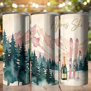 May include: Three stainless steel tumblers with a watercolor design. The design features a mountain range, evergreen trees, and the words "Apres Ski" in gold script. A champagne bottle and skis are also depicted.