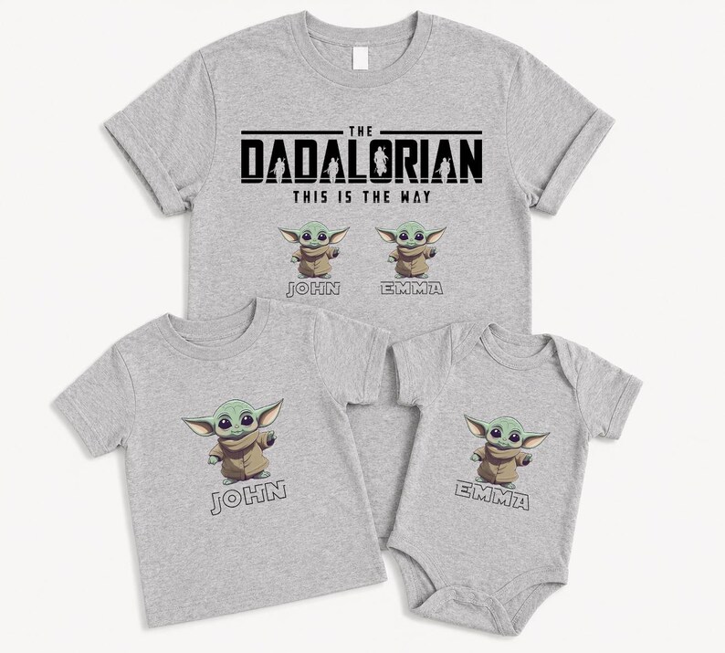 May include: Four light grey t-shirts and a babygrow. The largest shirt reads "THE DADALORIAN THIS IS THE WAY" with Grogu graphics. Smaller shirts and babygrow have Grogu graphics and names. Family matching apparel.
