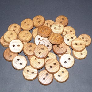 Puede incluir: Un montón de botones de madera en varios tonos de marrón. Los botones son redondos y tienen dos agujeros cada uno.