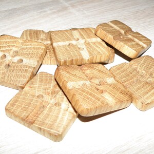 Könnte beinhalten: Ein Satz mit sechs Holz-Knöpfen, jeder mit einer quadratischen Form und einem Kreuzmuster. Die Knöpfe sind aus hellem braunem Holz gefertigt und haben ein natürliches, rustikales Aussehen.