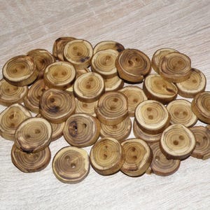 Peut inclure: Un tas de boutons en bois avec deux trous chacun. Les boutons sont circulaires, de couleur marron clair et présentent des motifs de grain de bois visibles. Fabriqués en bois naturel.