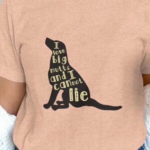 May include: A pink t-shirt with a black silhouette of a dog. The dog is made up of the words "I love big mutts and I cannot lie".