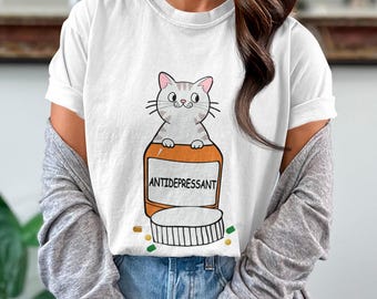 May include: White t-shirt with a cartoon cat inside a pill bottle that says "ANTIDEPRESSANT".