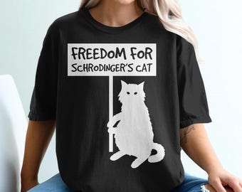 May include: Black t-shirt with a white graphic of a cat holding a sign that says "Freedom for Schrodinger's Cat".