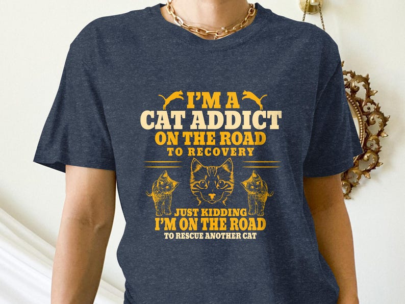 a man wearing a blue t - shirt that says i'm a cat addict