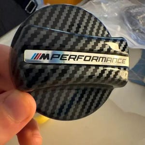 May include: Black carbon fibre fuel cap with a silver "M Performance" logo.