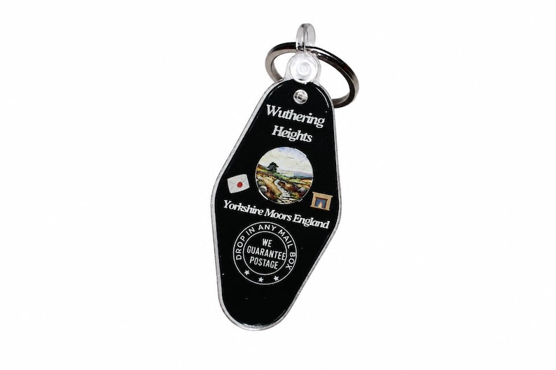 May include: Black acrylic keychain with a metal ring. The keychain features the text "Wuthering Heights Yorkshire Moors England" with a landscape image. Additional text includes "Drop in any mailbox" and "We guarantee postage."