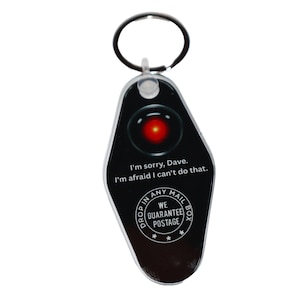 May include: Black keychain with a design featuring a red eye and the text "I'm sorry, Dave. I'm afraid I can't do that." The keychain also includes the text "Drop in any mail box, we guarantee postage."