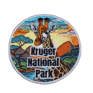 May include: A round embroidered patch with a colorful image of a giraffe in a savanna landscape. The text "Kruger National Park" is printed in black letters below the giraffe.