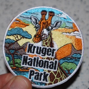 May include: Embroidered patch featuring a giraffe in a colorful landscape with the text "Kruger National Park".