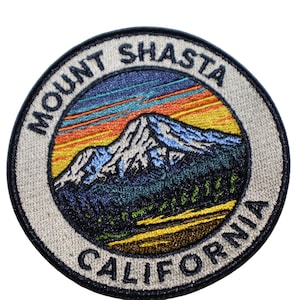 May include: Embroidered patch featuring Mount Shasta, California. The circular patch has a mountain scene with a colorful sunset and the words "Mount Shasta" and "California" in a circular design.