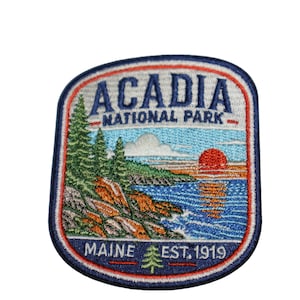 May include: A rectangular embroidered patch with rounded corners featuring a landscape of Acadia National Park. The design includes green pine trees, rocky cliffs, a blue ocean, and a red sun. Text reads ACADIA NATIONAL PARK and MAINE EST. 1919.