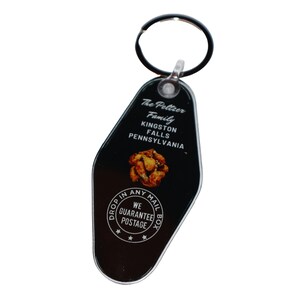 May include: Black and white motel key tag with the text "The Peltzer Family Kingston Falls Pennsylvania" and a circle with the text "Drop In Any Mail We Guarantee Postage Box".