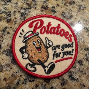 May include: A circular embroidered patch with a cream background and a red border. It features a cartoon potato character wearing a hat, walking, and giving a thumbs up. The text reads "Potatoes are good for you!" in red and black lettering.